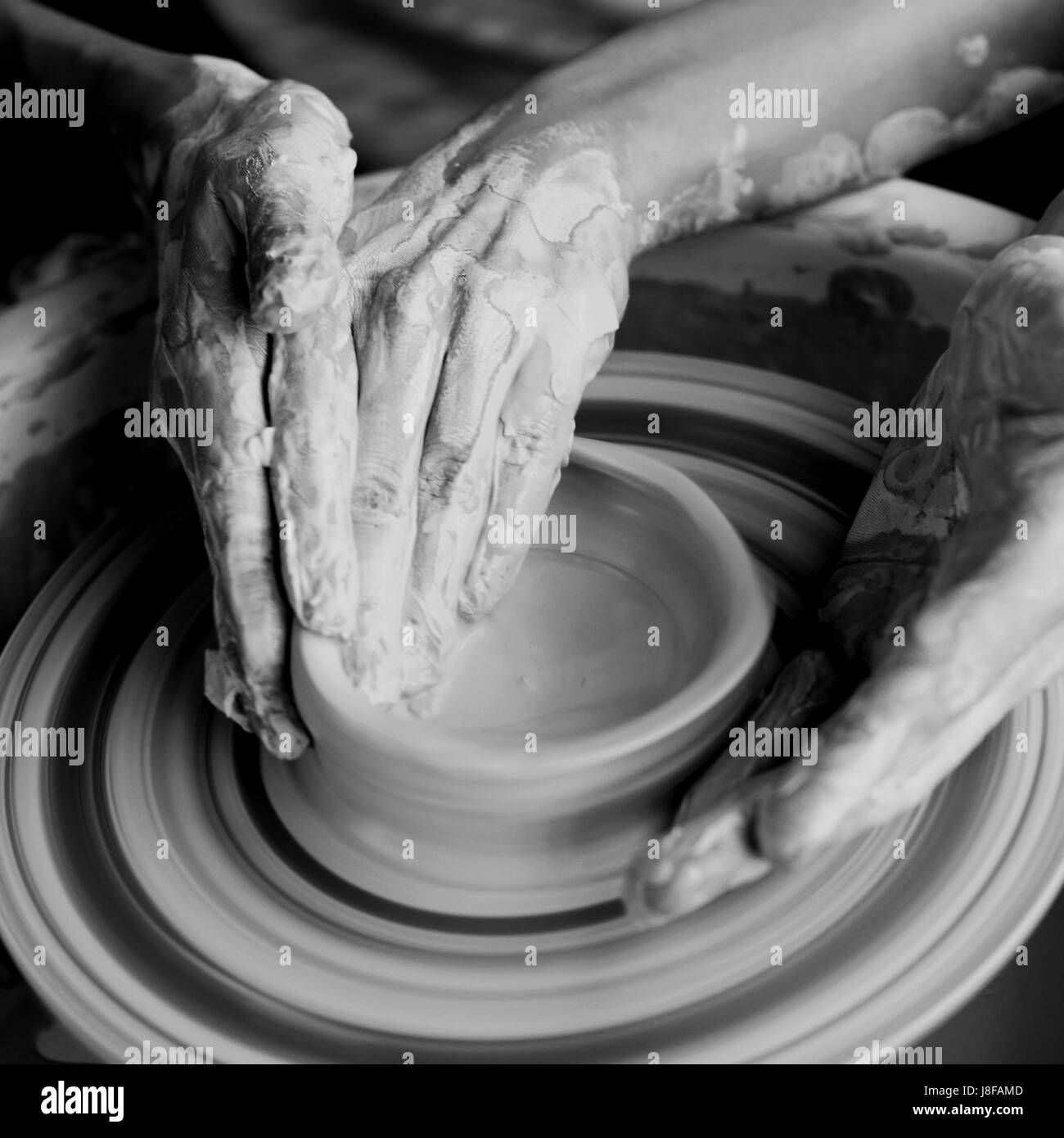 Couple working on pottery wheel. Top view of woman and man hands making ceramic pot or sculpting