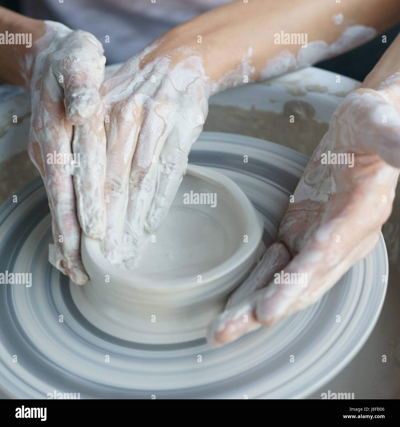 Couple working on pottery wheel. Top view of woman and man hands making ...
