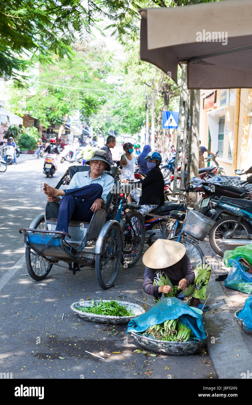NHA TRANG, VIETNAM - JANUARY 20: Vietnamese woman in traditional conical hat is sorting greens on the street of Nha Trang on January 20, 2016 in Nha T Stock Photo