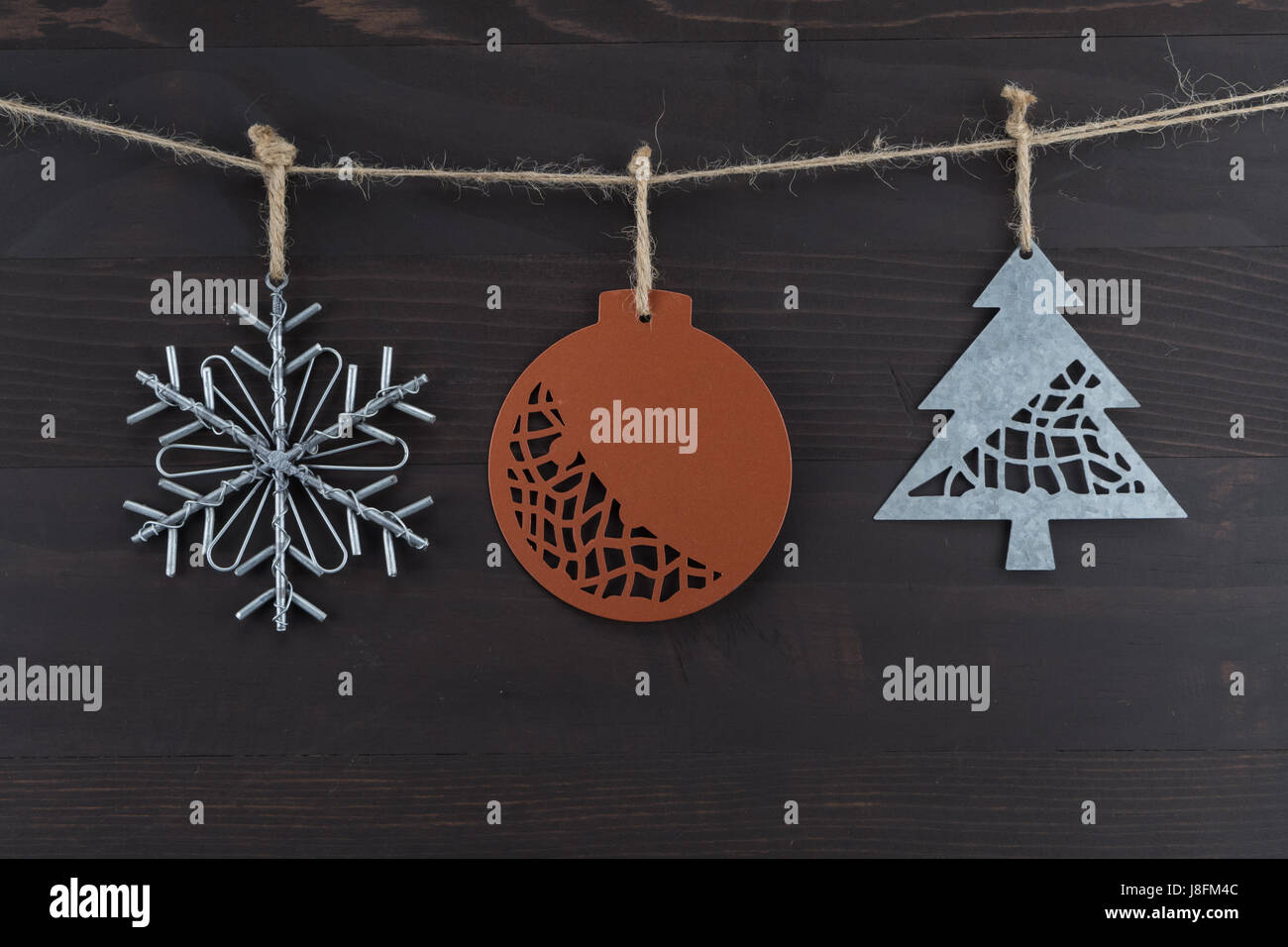 Three Rustic Metal Christmas Ornaments Hanging from Twine Stock Photo