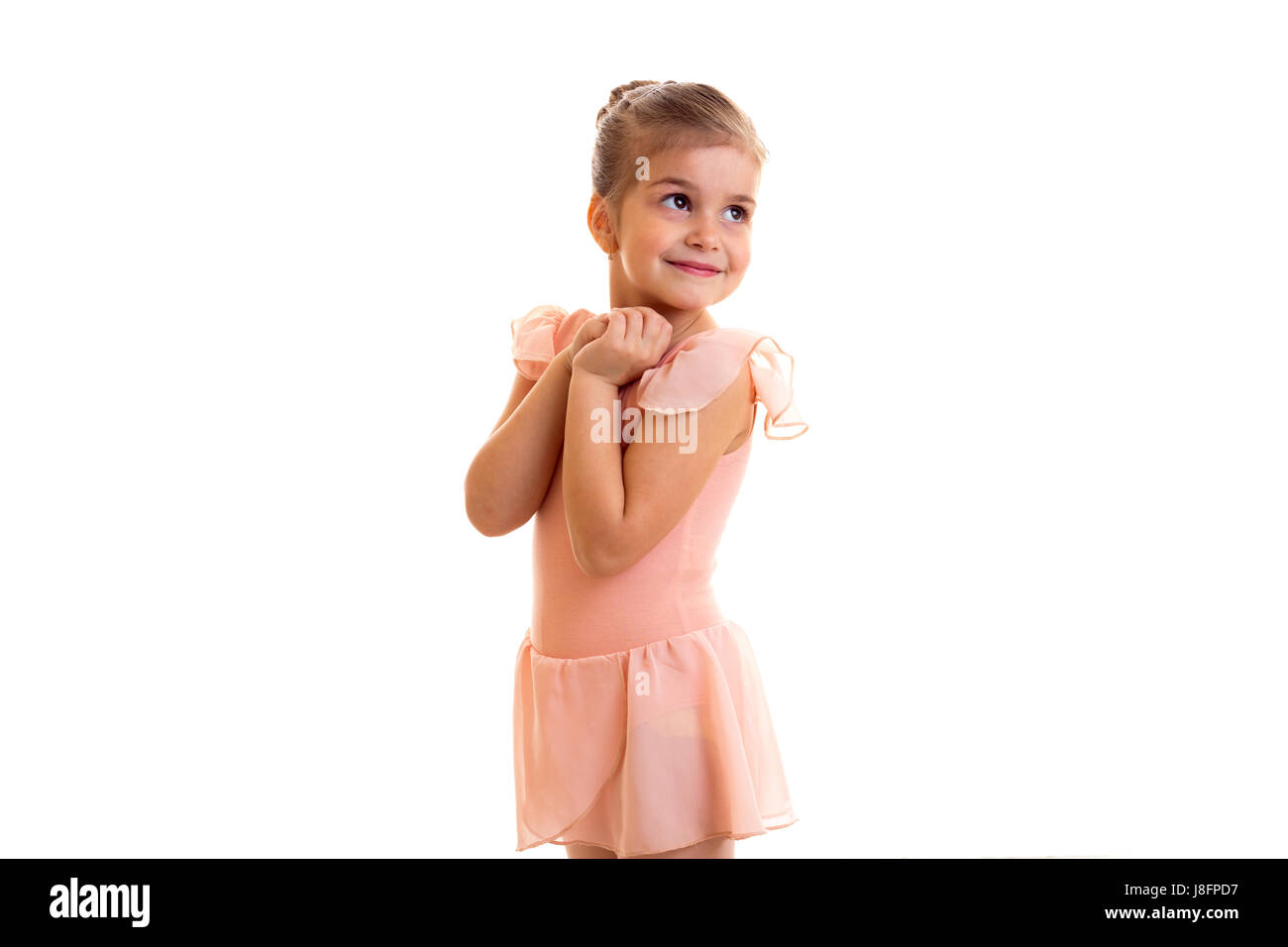Little positive girl in pink dress dancing on white background in