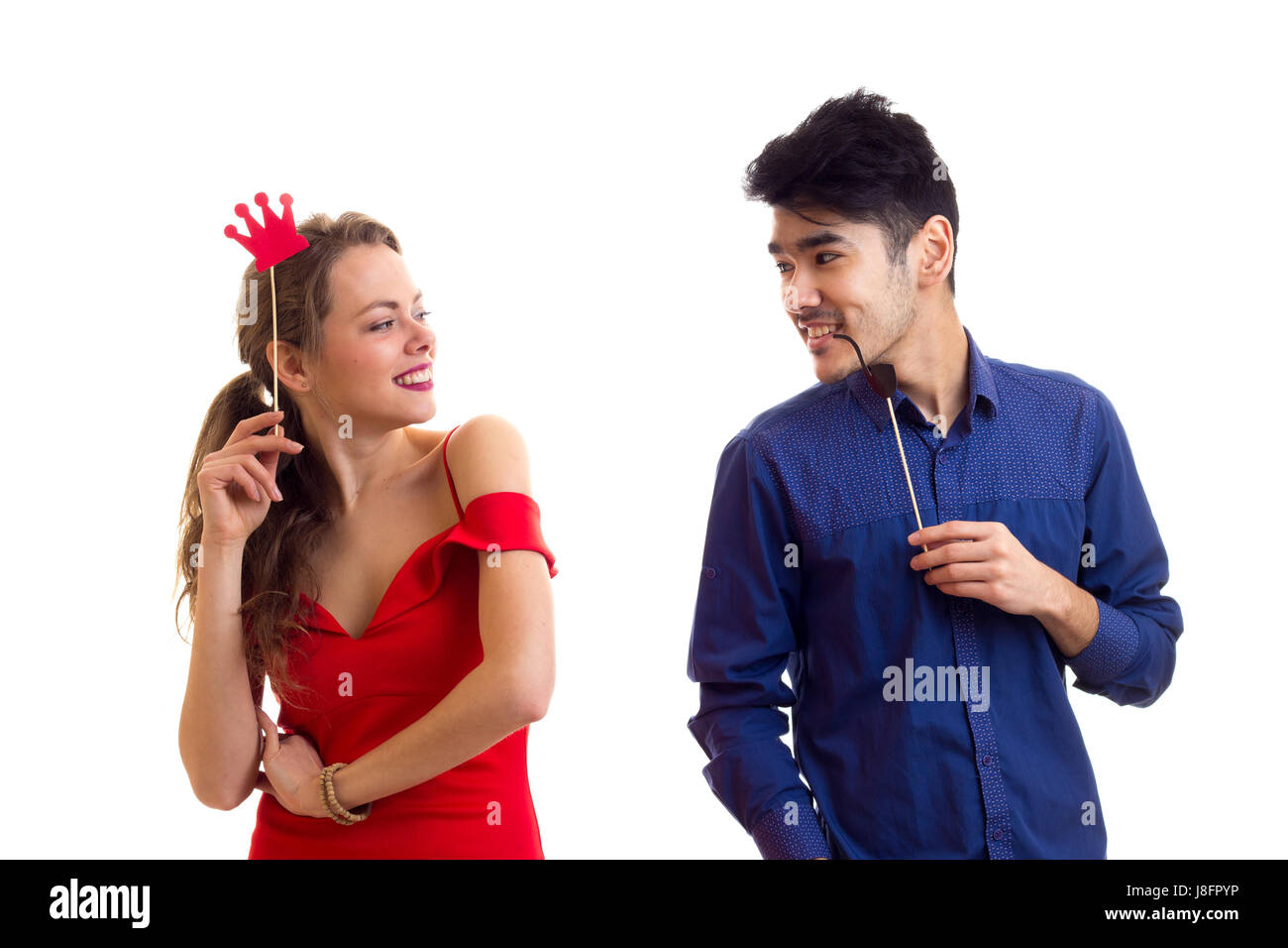 Young smiling woman with long blond hair in red dress and young handsome man with dark hair in blue shirt holding cardboard sticks of smoking pipe and Stock Photo