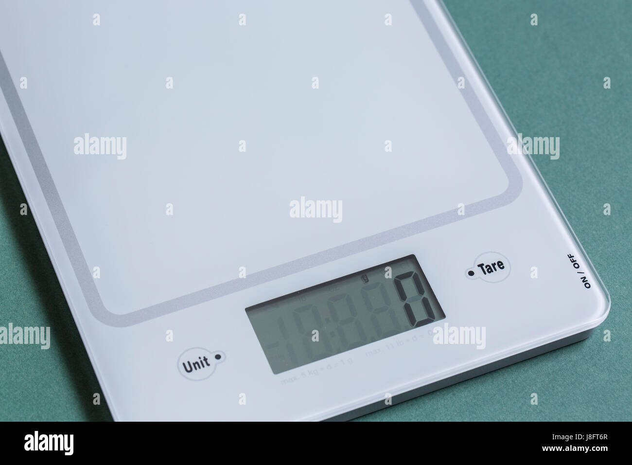 Empty digital kitchen scale on green paper background. Stock Photo