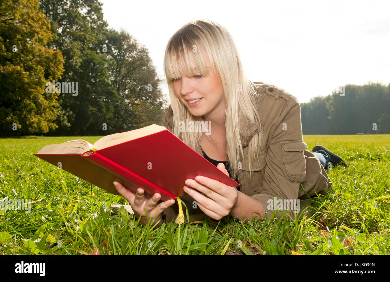 young woman reading book on a meadow Stock Photo