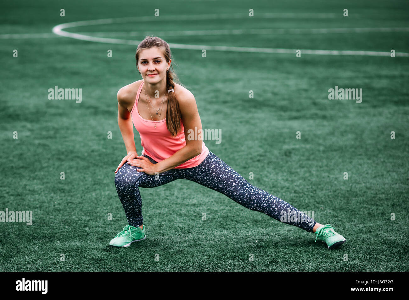 A beautiful muscular girl in tights and a vest makes a warm-up at the  stadium. Cross fit, fitness, healthy lifestyle Stock Photo - Alamy