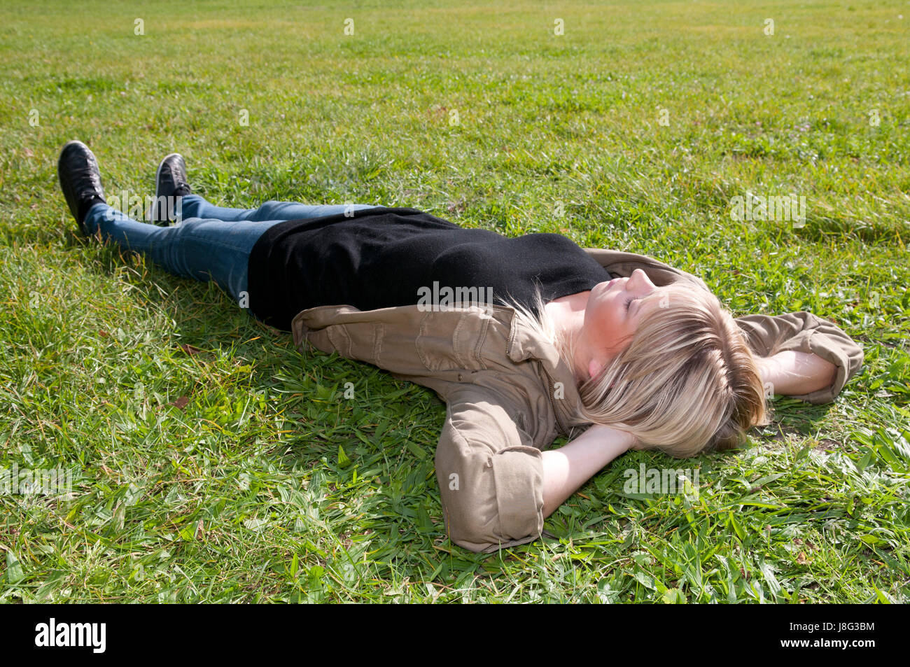 young woman lying on a lawn Stock Photo