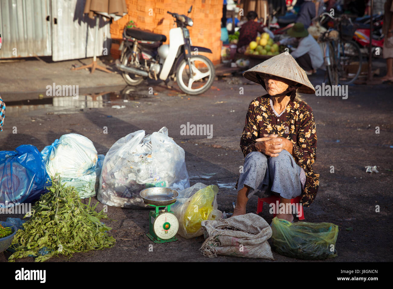 Nha Trang, Vietnam - December 02, 2015: Old vietnamese woman is selling vegetables at the street market, Nha Trang, Vietnam on December 02, 2015. Stock Photo