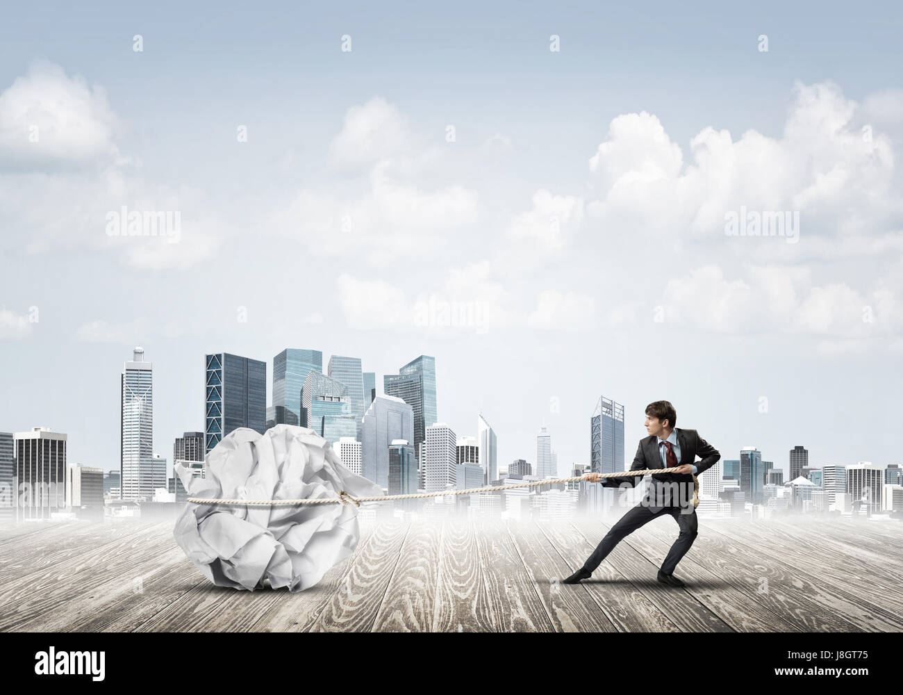 Man pulling with effort big crumpled ball of paper as creativity sign