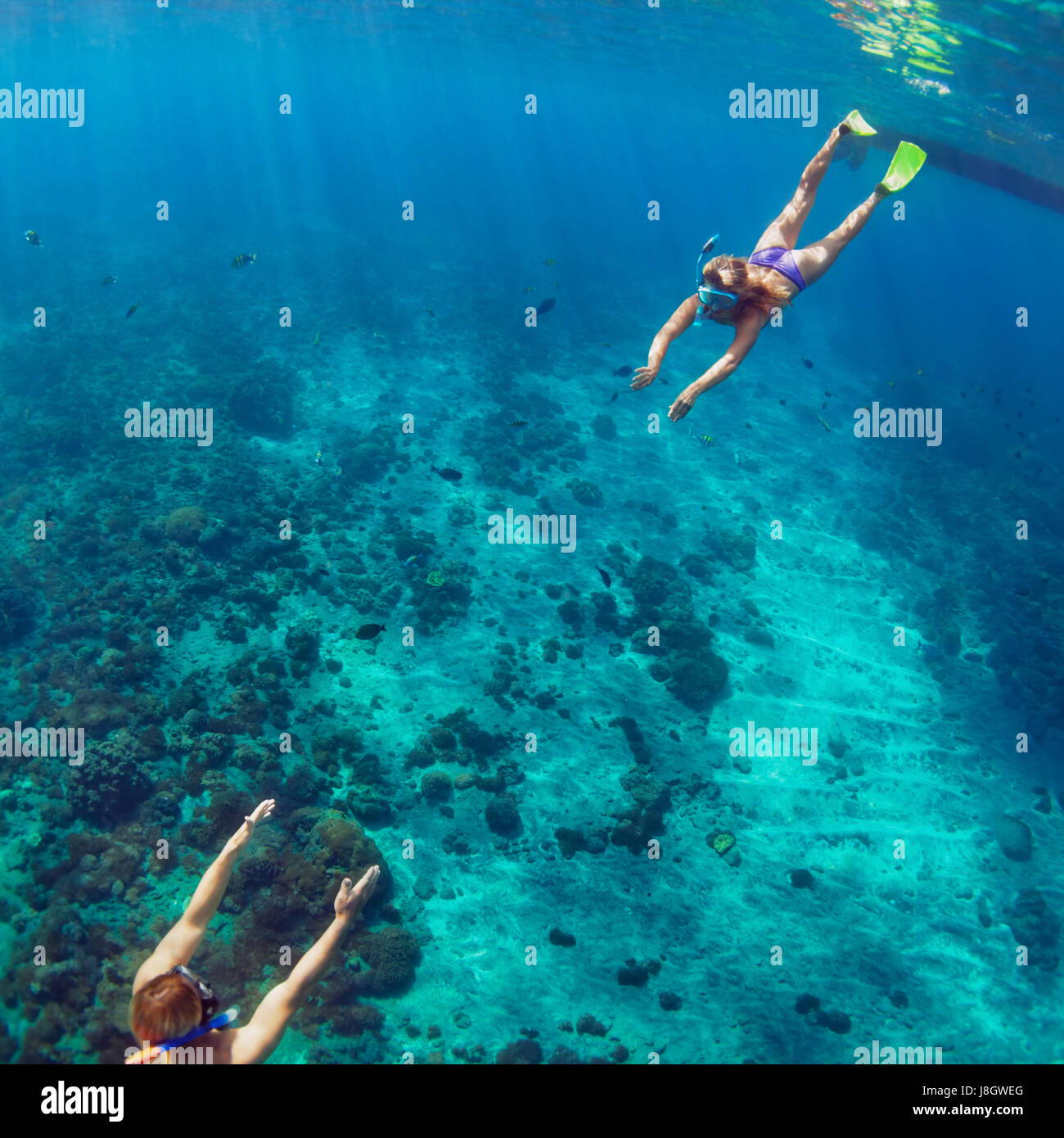 Happy family couple in snorkeling masks dive deep underwater with