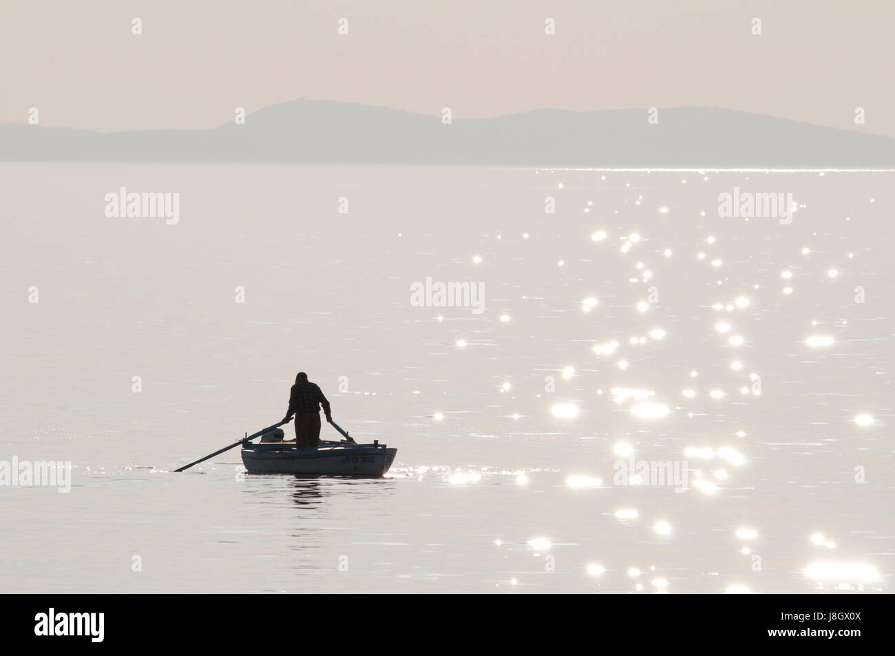 A silhouette of a man on a boat on the sparkling water Stock Photo - Alamy
