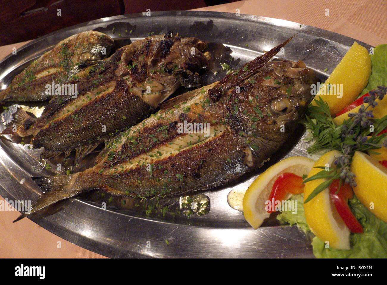 Delicious grilled fish with fresh herbs on a serving platter Stock Photo