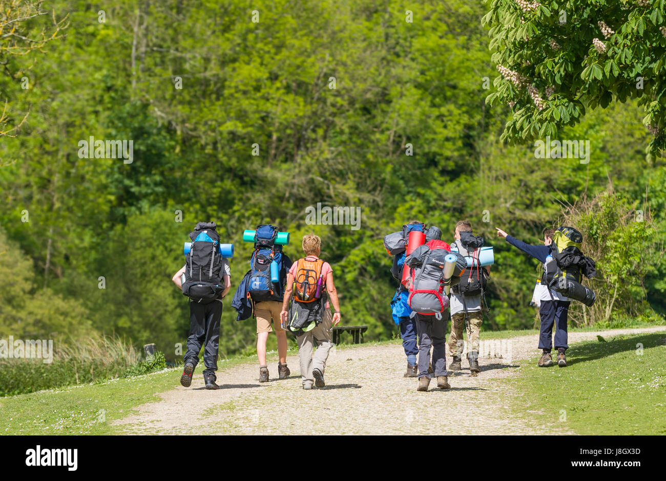 Group of young walkers with rucksacks walking in the countryside.in Spring. Stock Photo