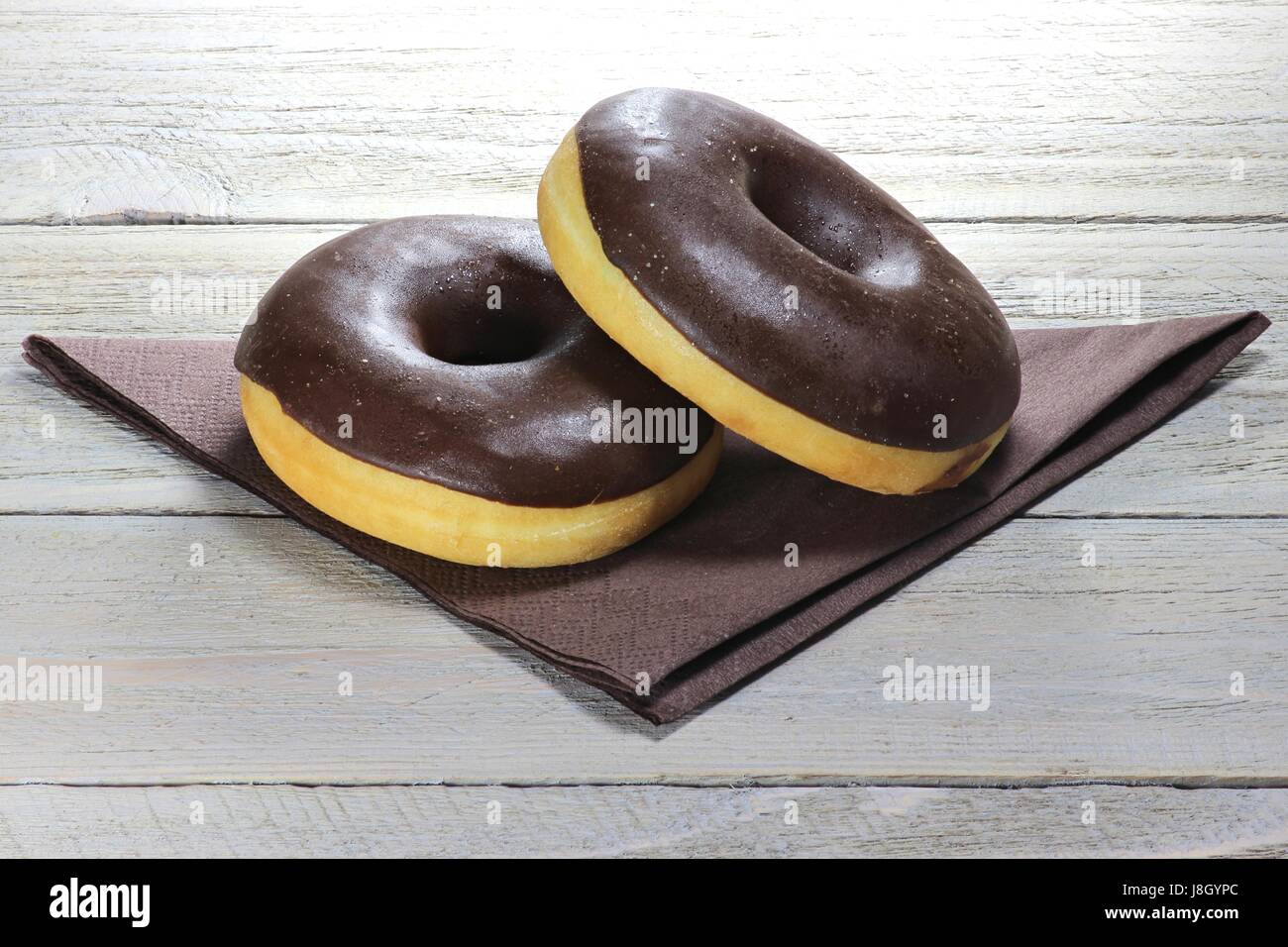chocolate iced donuts with napkin on wooden background Stock Photo - Alamy