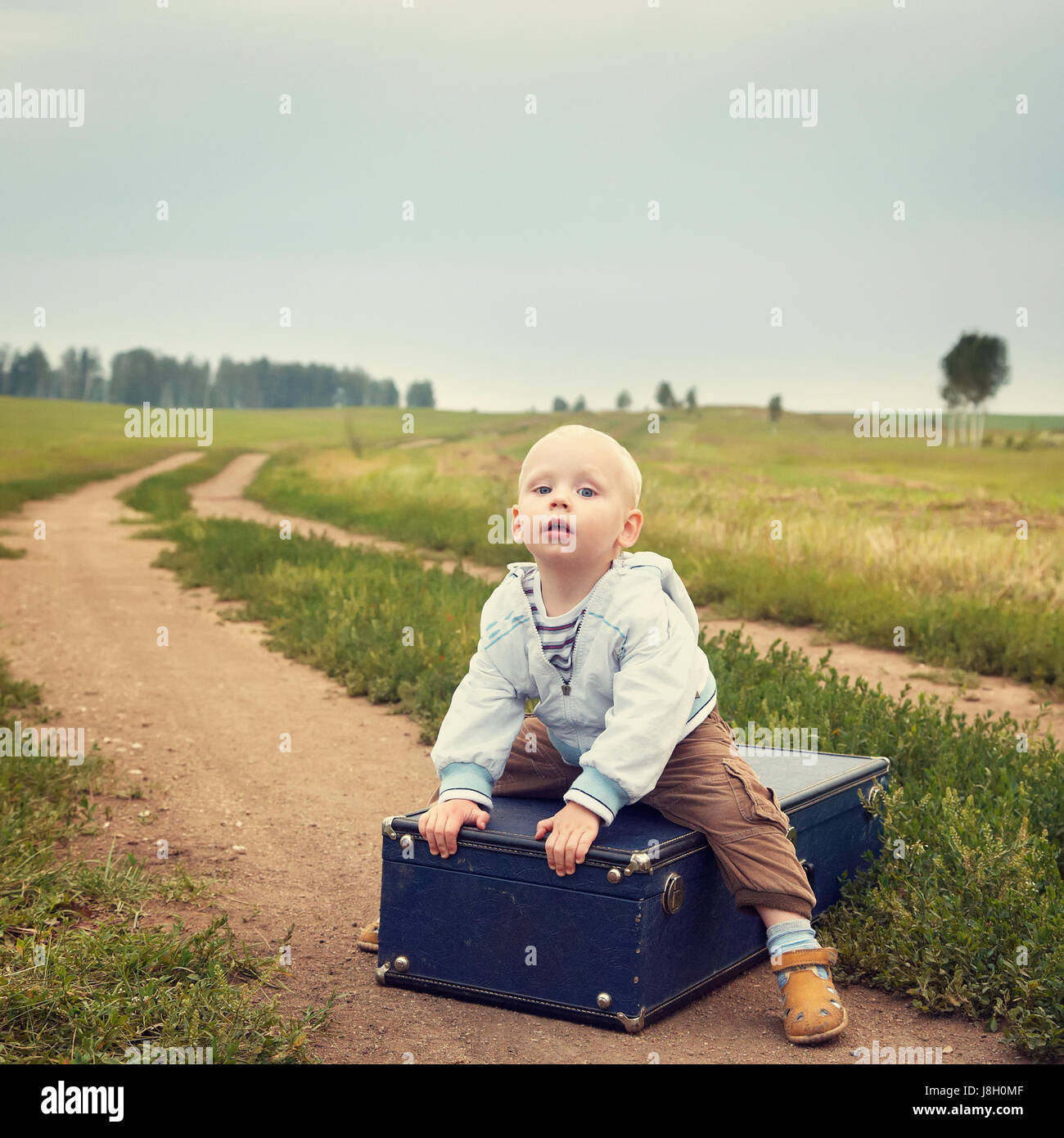 child sitting on a suitcase Stock Photo Alamy