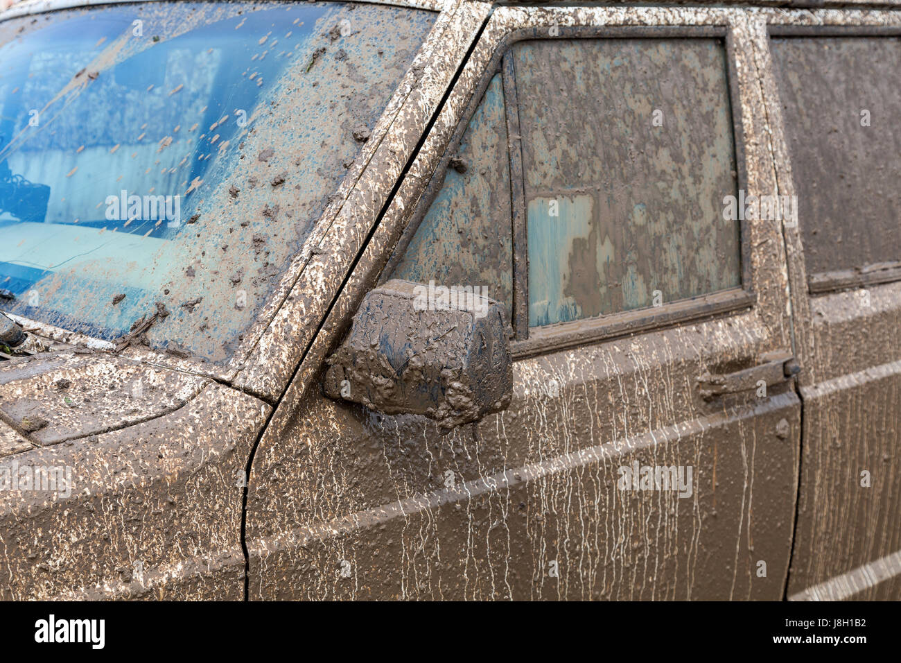Dirty SUV after driving in the rain on extremely dirty rural road Stock