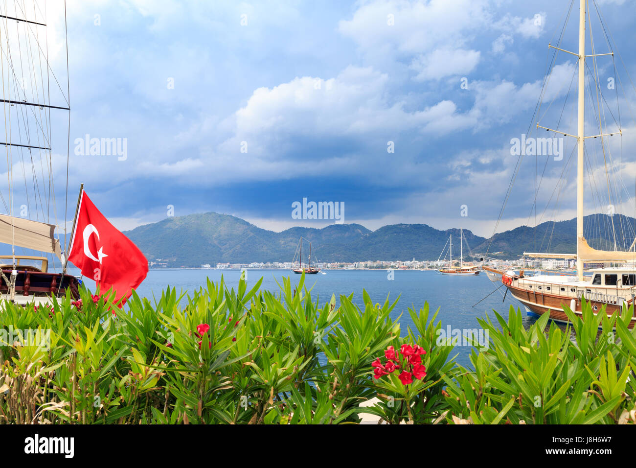 Oleander flowers and turkish flag in the seaport of marmaris with mountains background Stock Photo