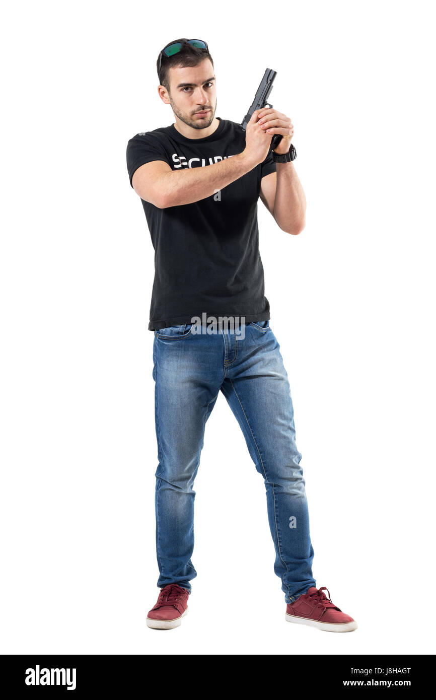 Serious cautious policeman in plain clothes holding gun with both hands. Full body length portrait isolated on white studio background. Stock Photo