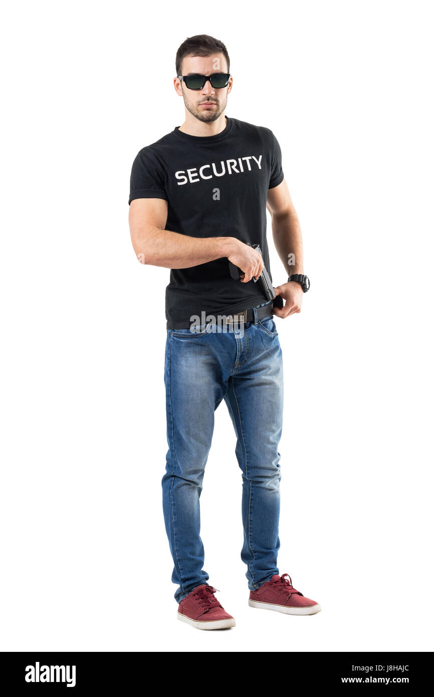 Undercover police man taking handgun from belt looking at camera. Full body length portrait isolated on white studio background. Stock Photo