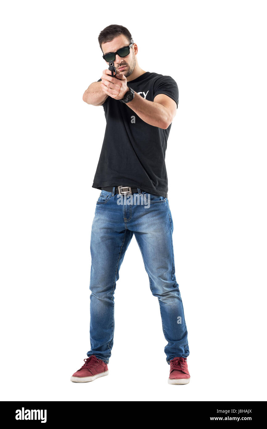 Plain clothes undercover cop aiming gun at viewer wearing sunglasses. Full body length portrait isolated on white studio background. Stock Photo