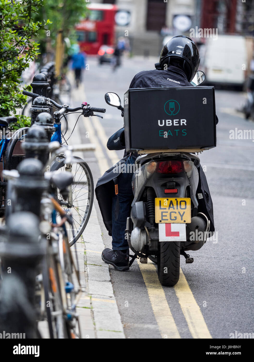 An Uber Eats food delivery courier waits for work in Central London