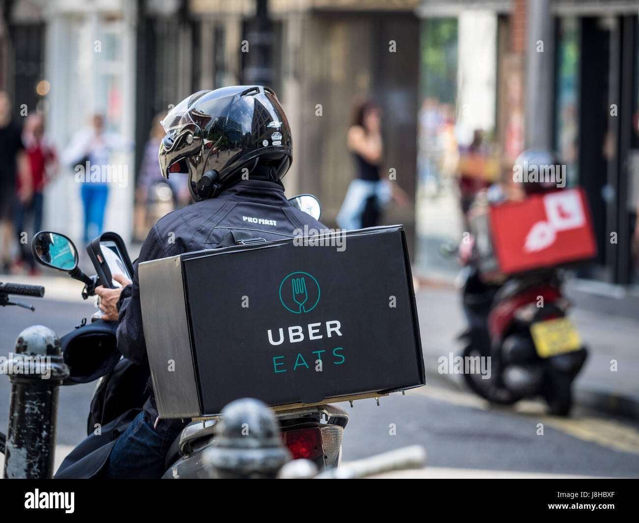 An Uber Eats food delivery courier waits for work in Central London