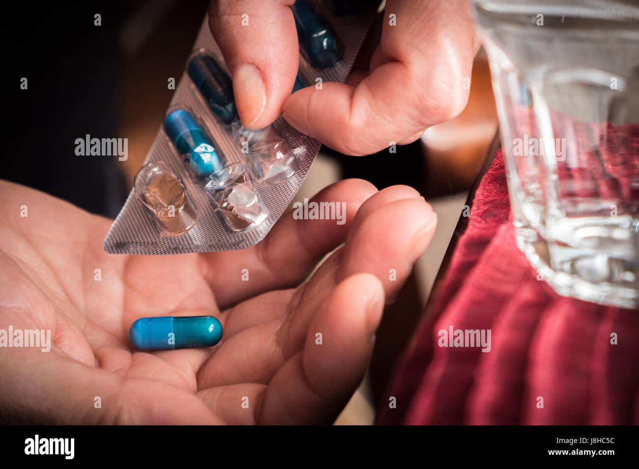 Women take blue capsule with left hand from a container pills Stock