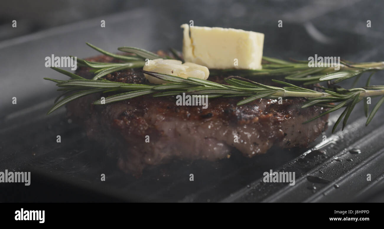 cooking rib eye steak with herbs on grill pan Stock Photo Alamy