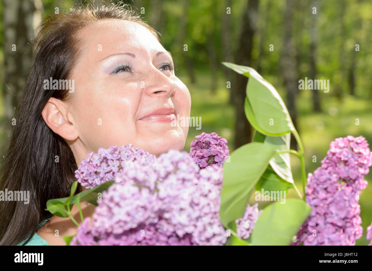 Happy woman with a bouquet of flowers smiling in the park Stock Photo ...