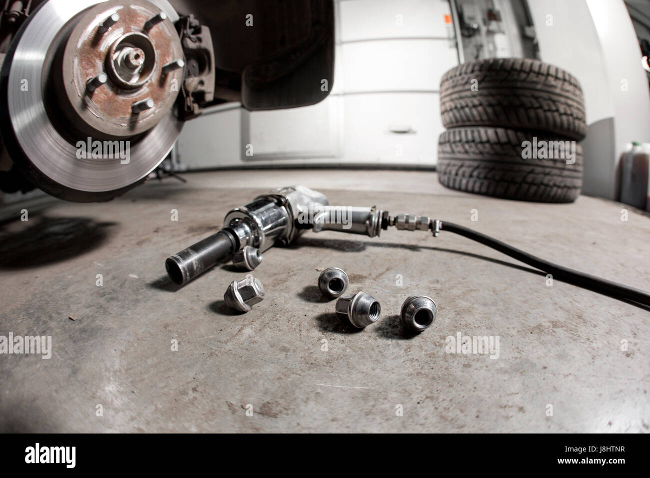 air gun to tighten a tire bolts on a suspended car at an auto shop