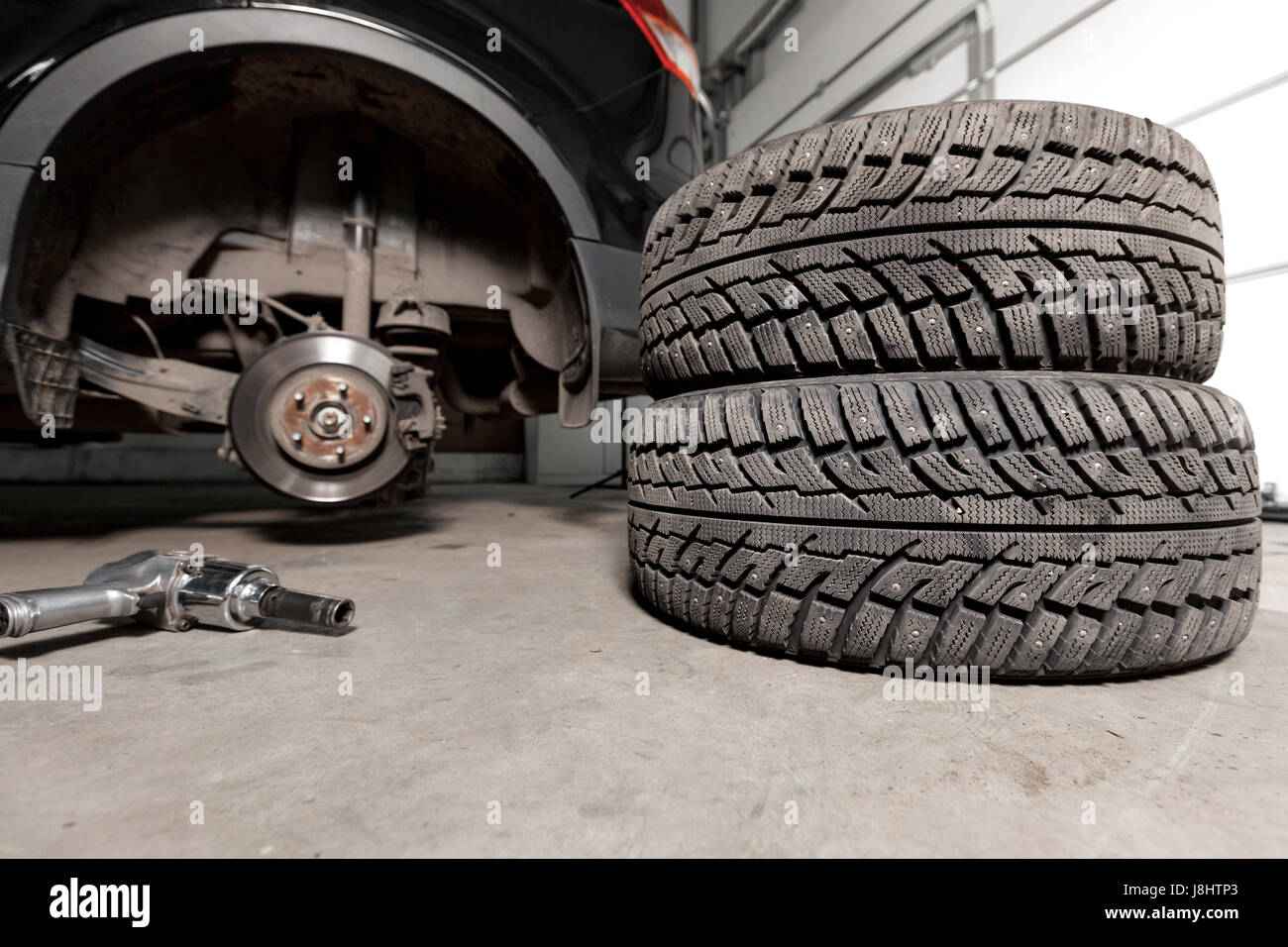 air gun to tighten a tire bolts on a suspended car at an auto shop