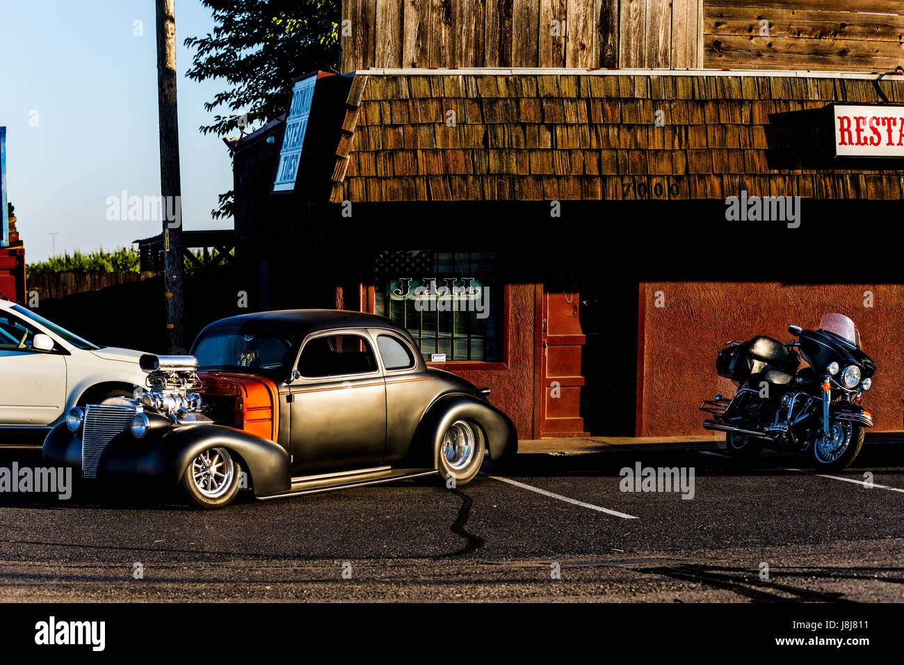 A Harley Davidson Motorcycle and a custom 1940 Ford Coupe parked at a bar in rural California Stock Photo