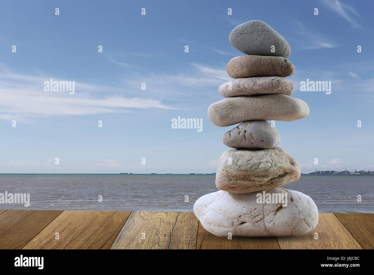Balance Stones stacked to pyramid in sea and blue sky background to Spa ideas design or freedom and stability concept on rocks. Stock Photo