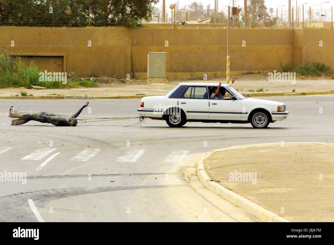 Using a car, Iraqi civilians drag a statue of Saddam Hussein down the streets of Baghdad, Iraq, during Operation IRAQI FREEDOM. Stock Photo
