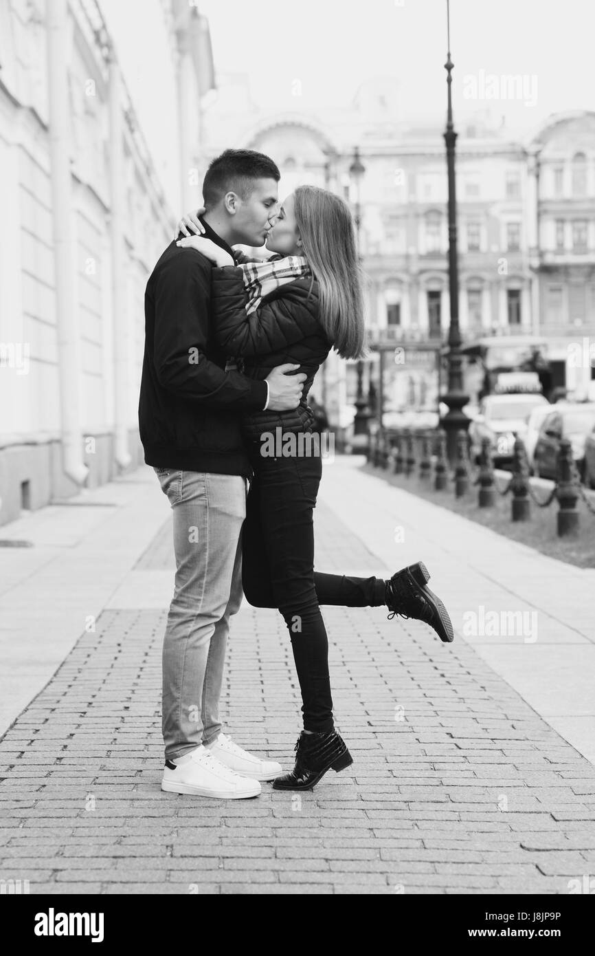 Young beautiful couple in love kissing and hugging at city street on