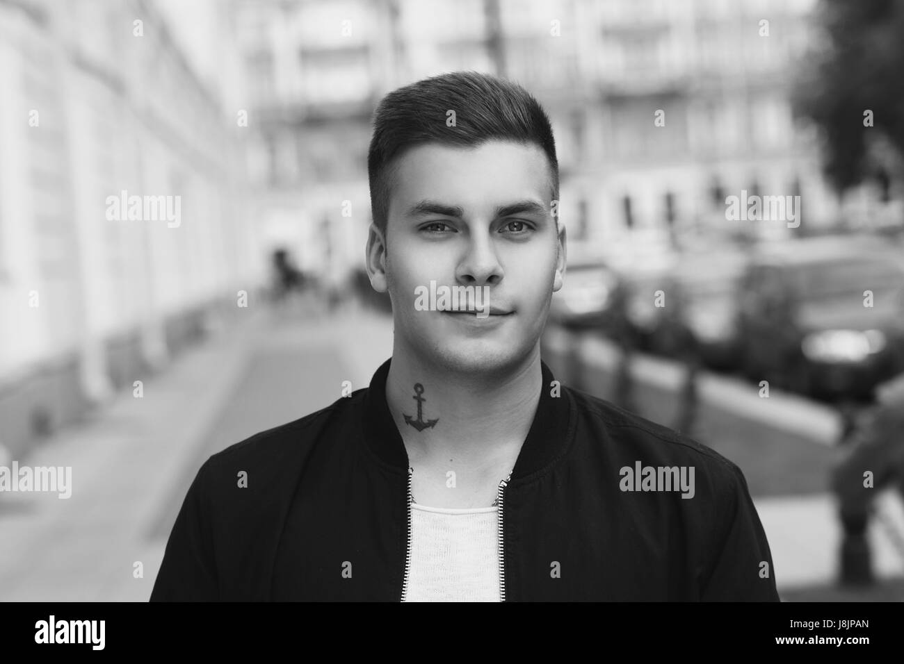 Outdoor street portrait of young handsome man with short haircut