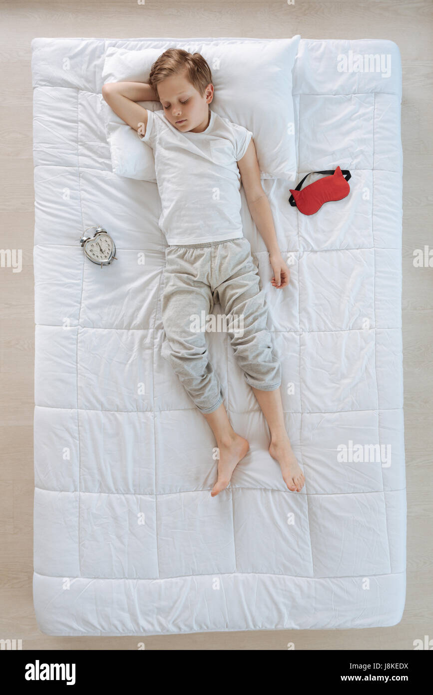 Peaceful sleep. Top view of a cute pleasant nice boy resting in his bed