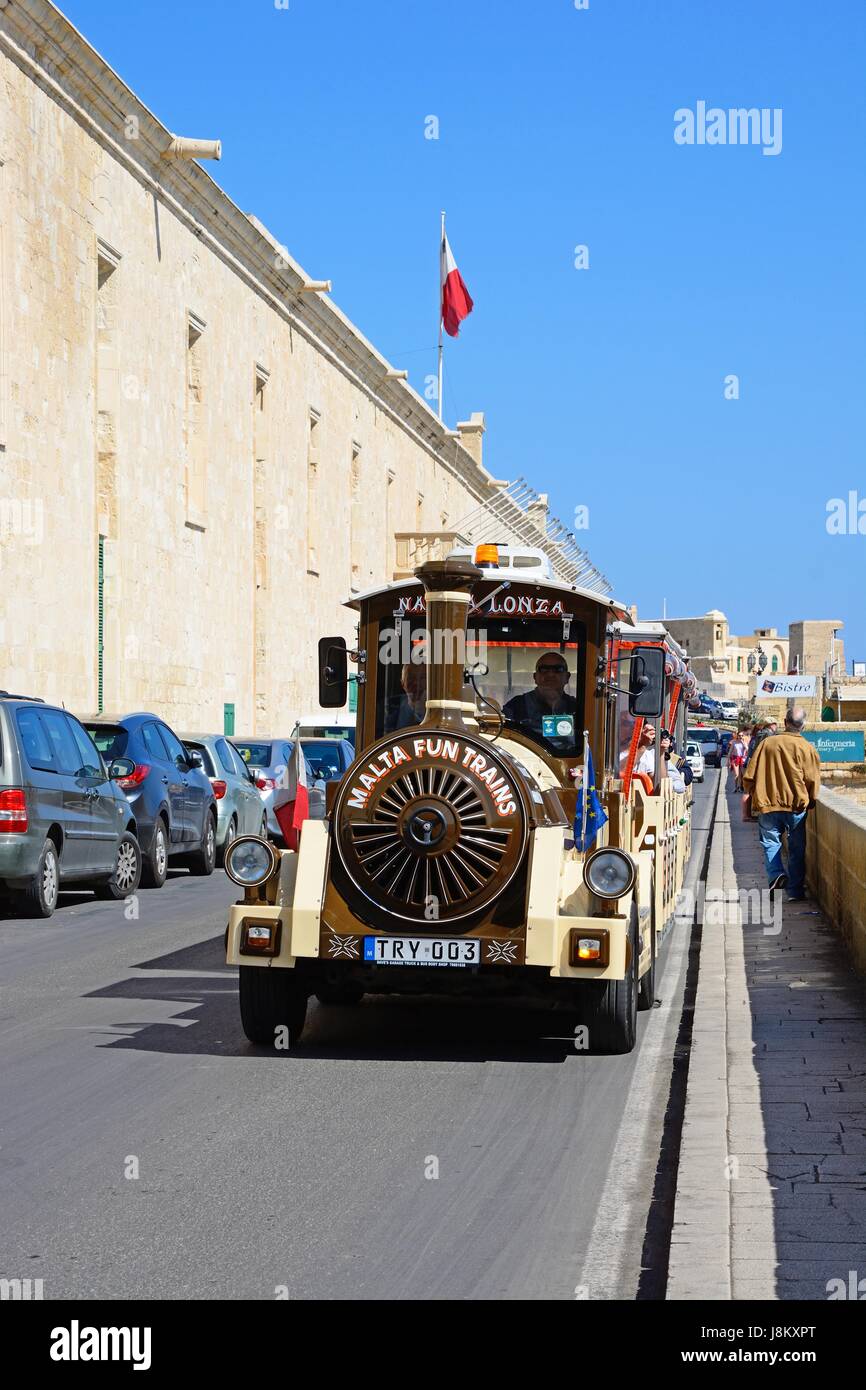 Tourist land train passing the Holy Infirmary along Triq Il-Mediterran, Valletta, Malta, Europe. Stock Photo