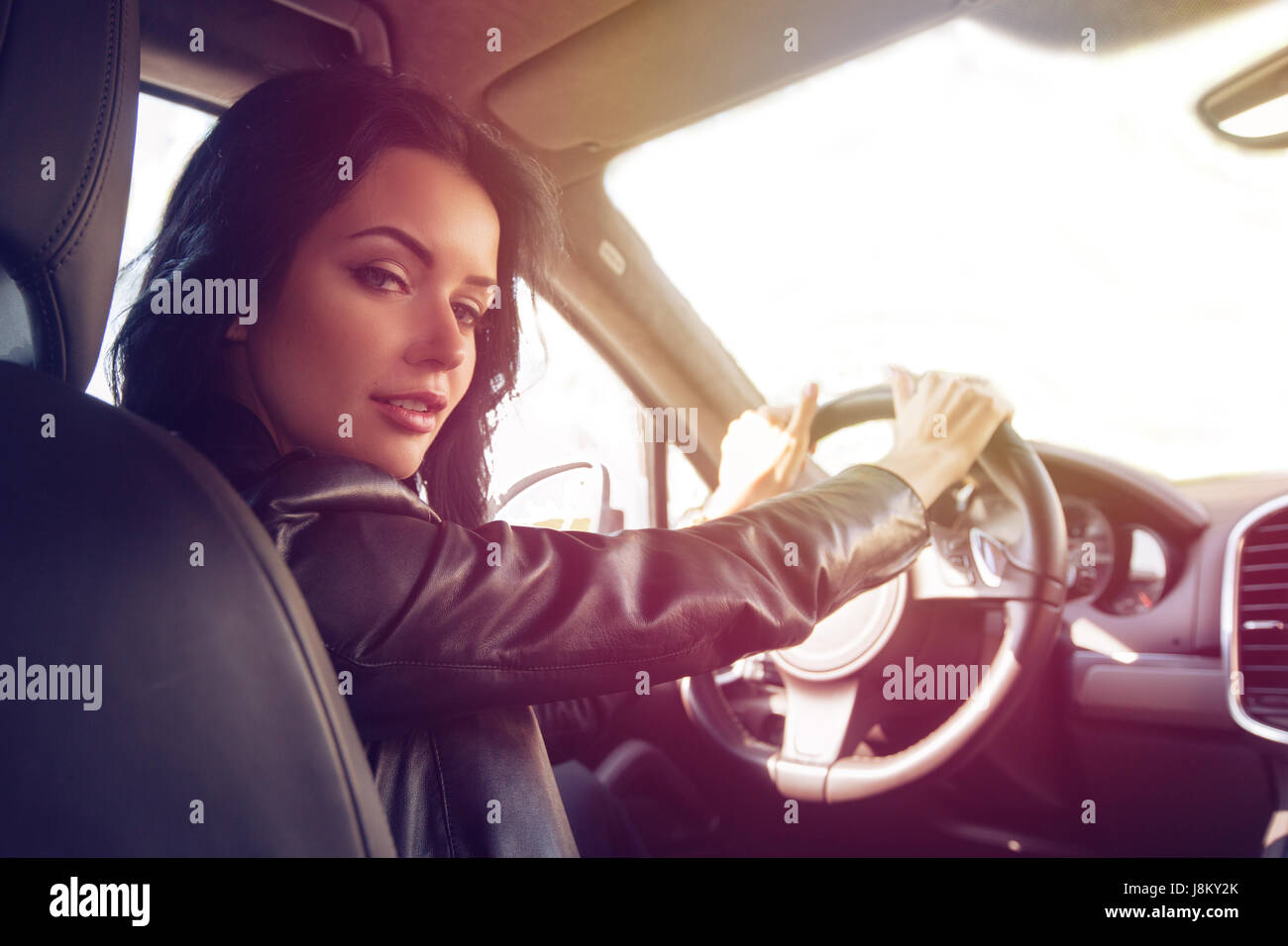 Beautiful brunette woman steers car expensive car Stock Photo