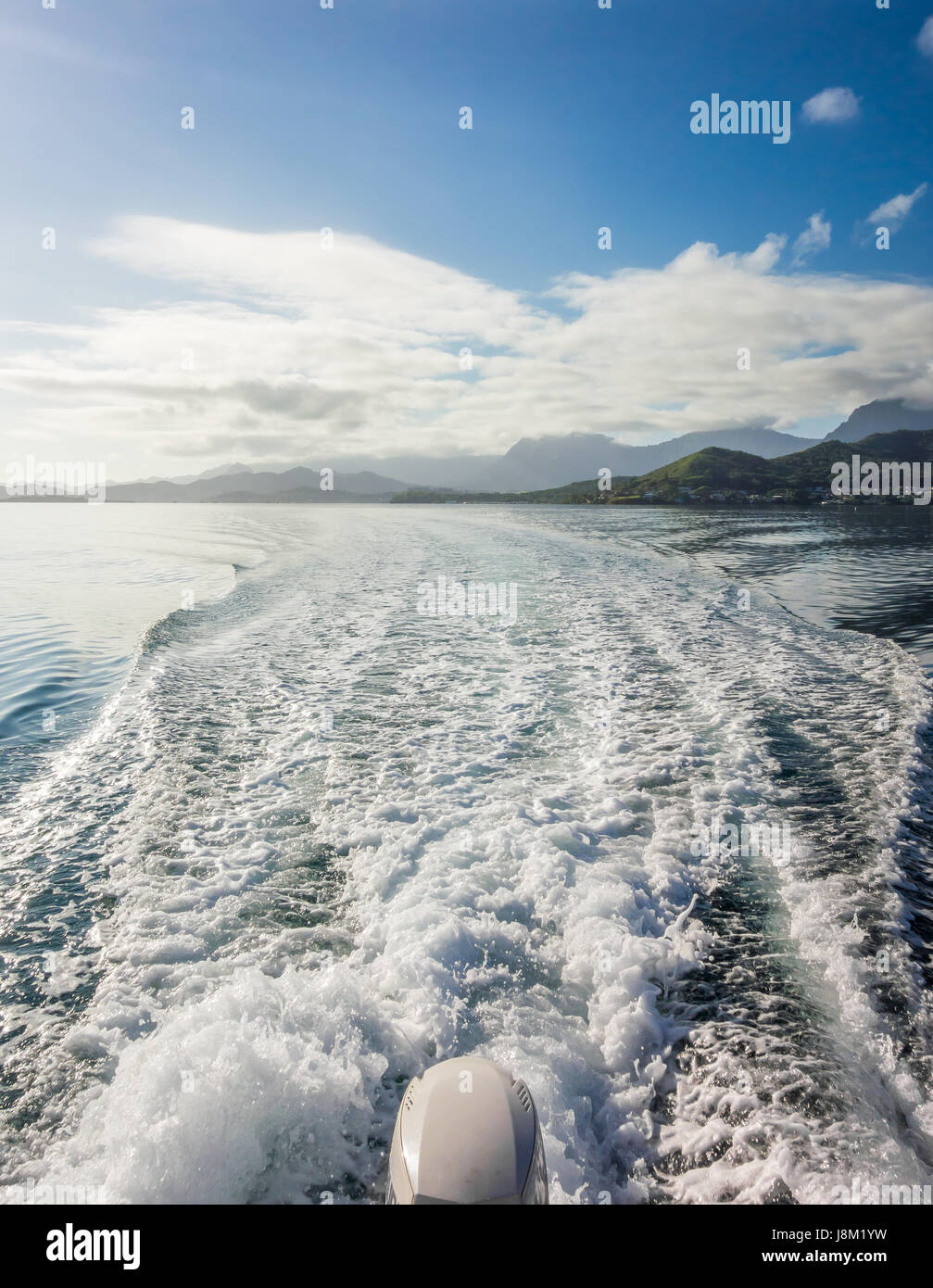 The waves and splashing water viewed from the back of a boat speeding across the blue water of Kaneohe Bay on Oahu, Hawaii. Stock Photo