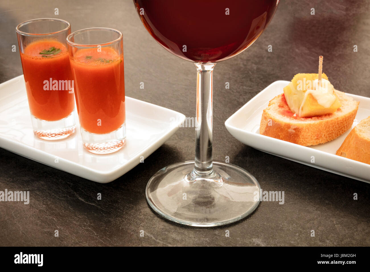 Spanish tapas in a modern bar. A glass of red wine, two shots of