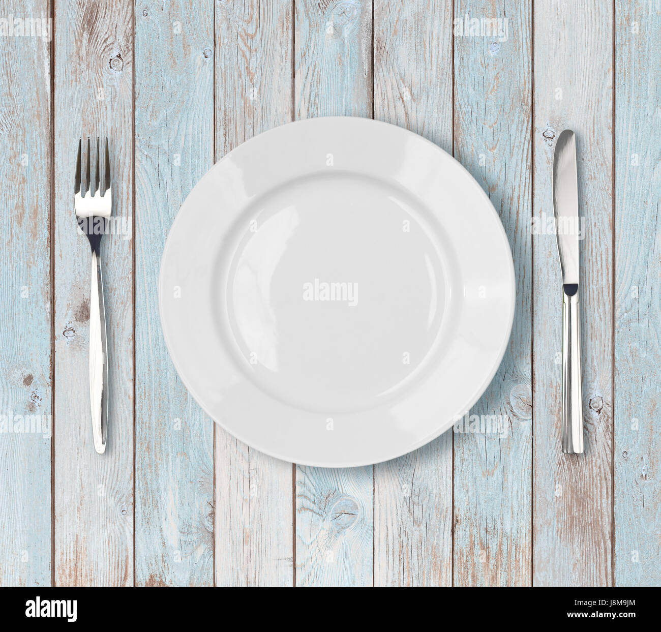 white empty dinner plate setting on blue wooden table Stock Photo