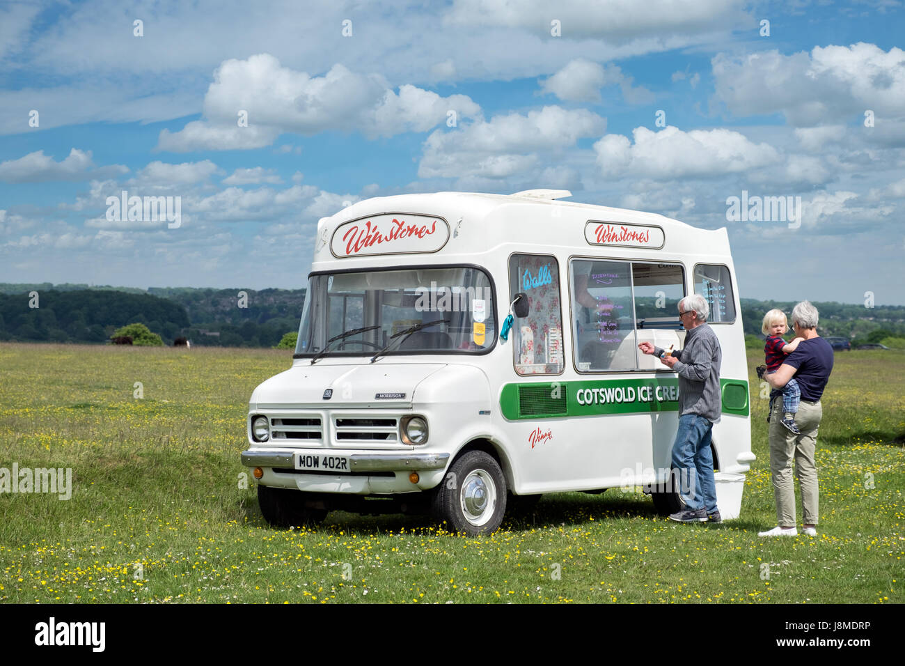 Vinny the vintage Bedford ice cream van owned by Winstones, selling ices to a family on Minchinhampton Common in the Cotswolds, Gloucestershire, UK Stock Photo