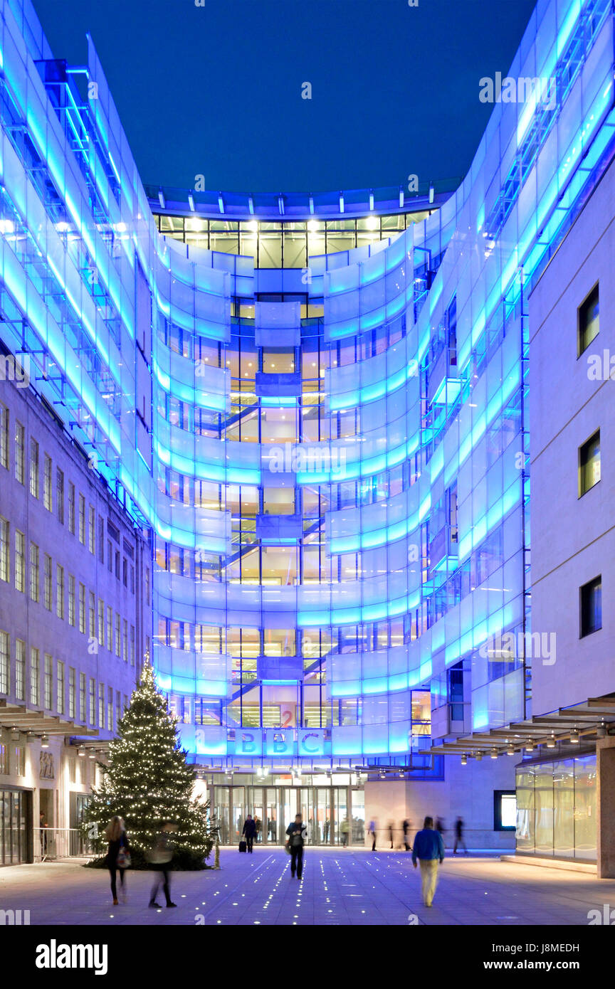 New BBC eastern extension building beside original Broadcasting House lit with blue lighting with Christmas tree in courtyard leading to BBC entrance Stock Photo