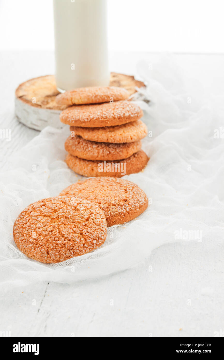 A stack of round shortbread cookies and a bottle of milk, on a white ...