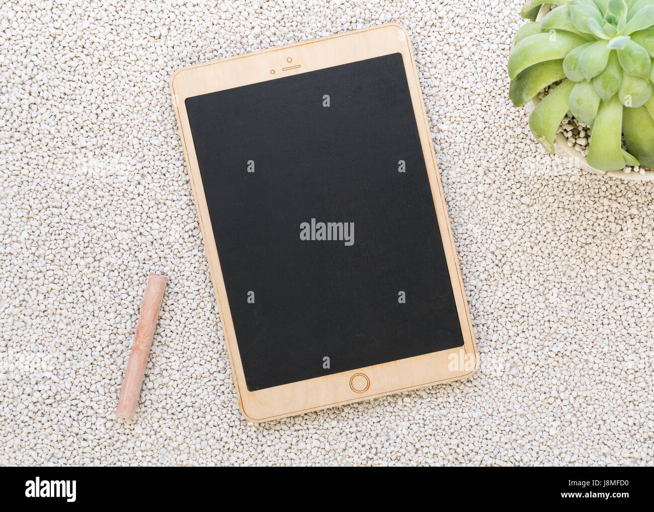 Tablet shaped chalk board on white pebbles background, flat lay Stock Photo