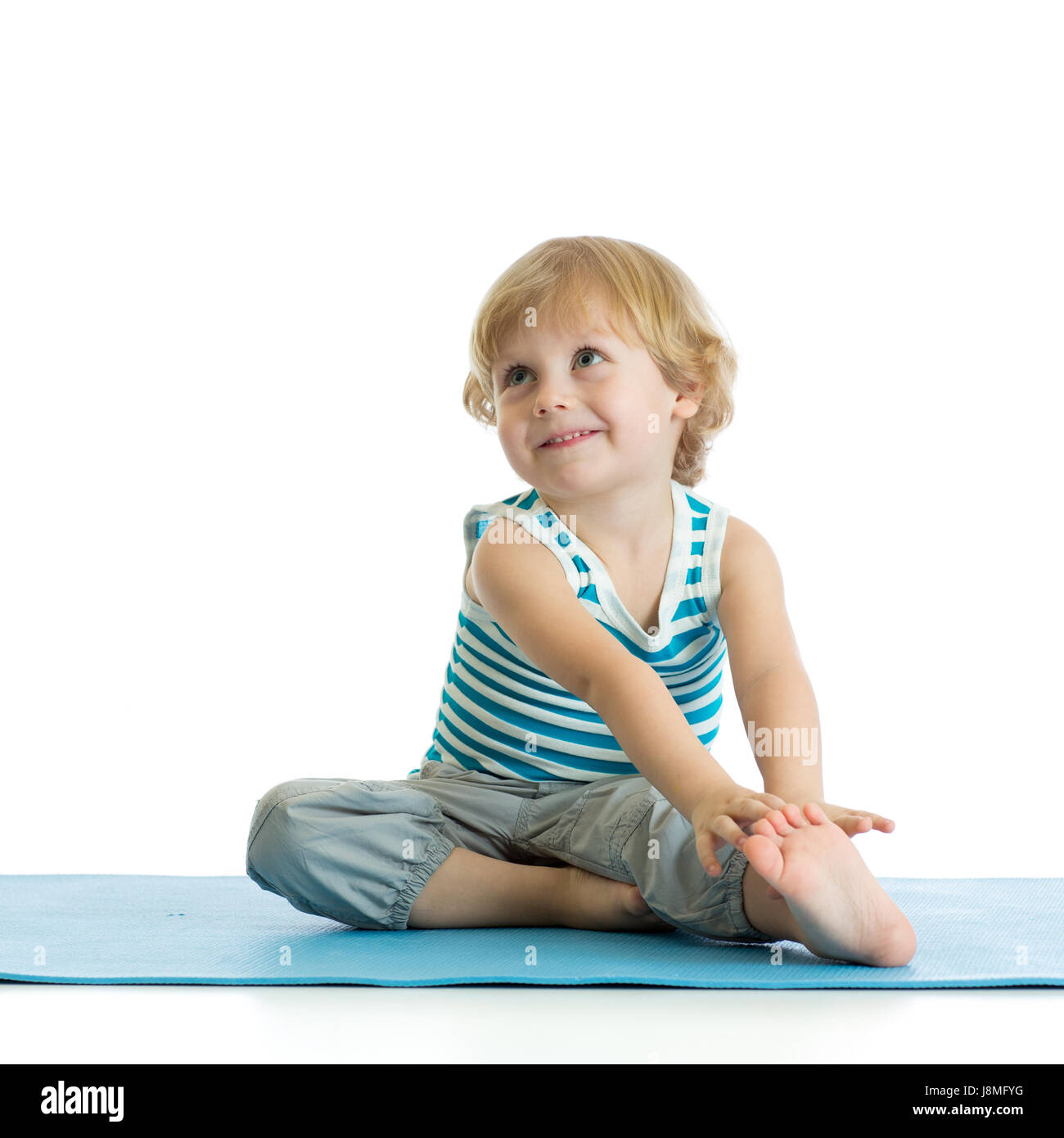 Child boy practicing yoga, stretching in exercise. Kid isolated over white background Stock Photo