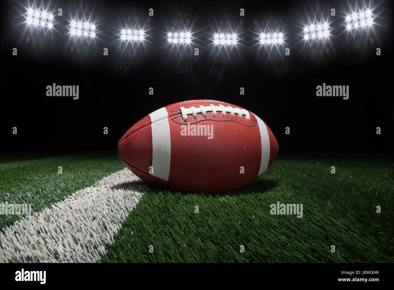Low angle view of college style football on a yard line of a football field under stadium lights Stock Photo