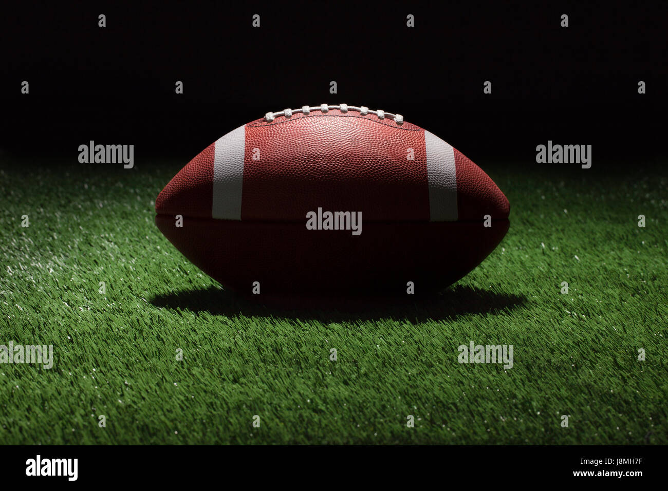 College style football on grass field at night shot with spot lighting Stock Photo