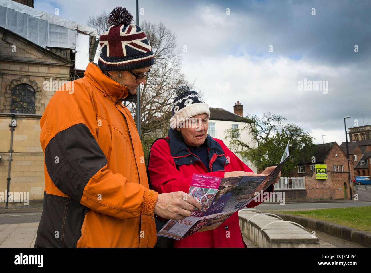 UK, England, Derbyshire, Derby, tourists wrapped up for bad weather looking at map Stock Photo