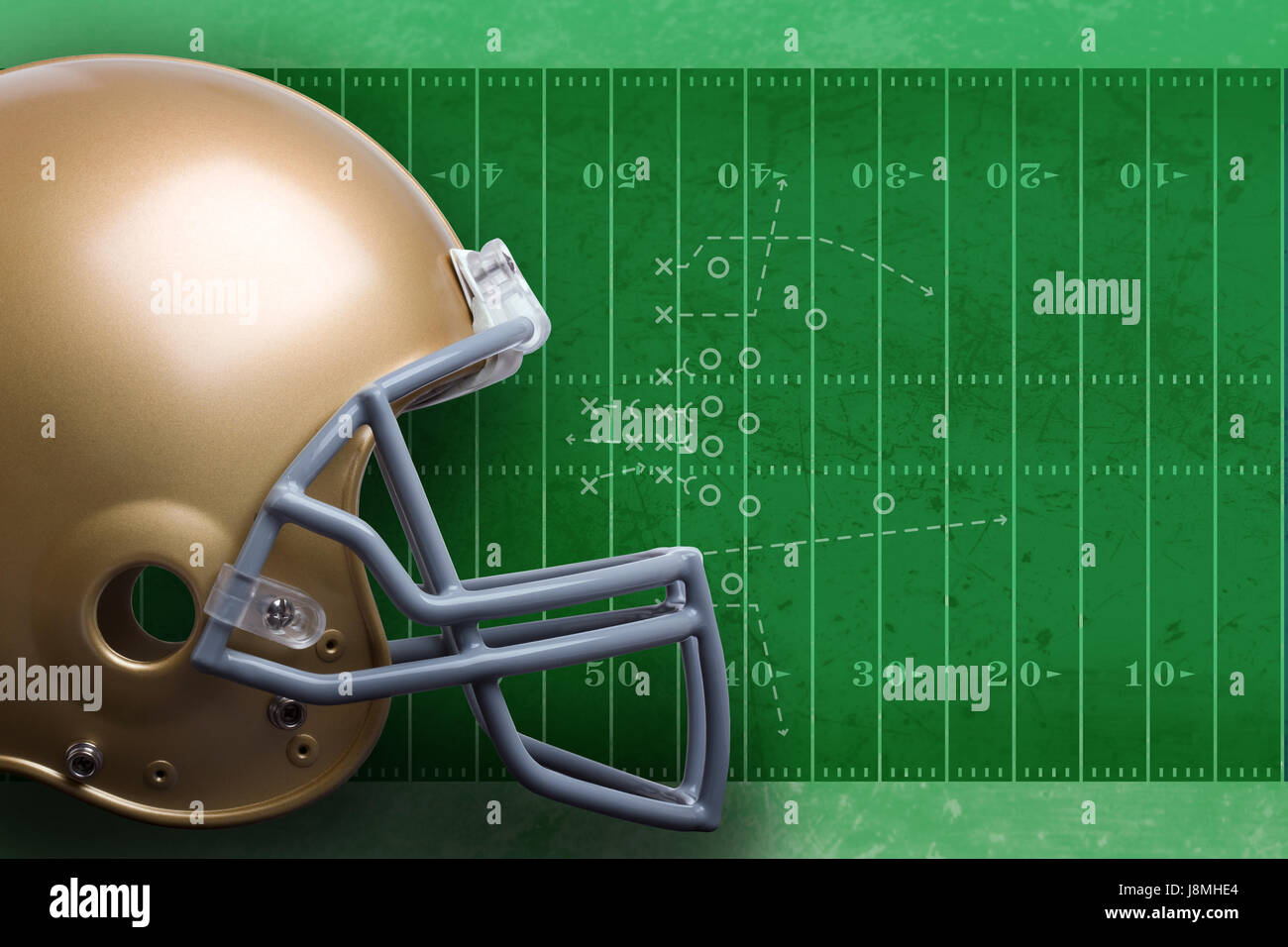 A gold football helmet in profile view against a textured green